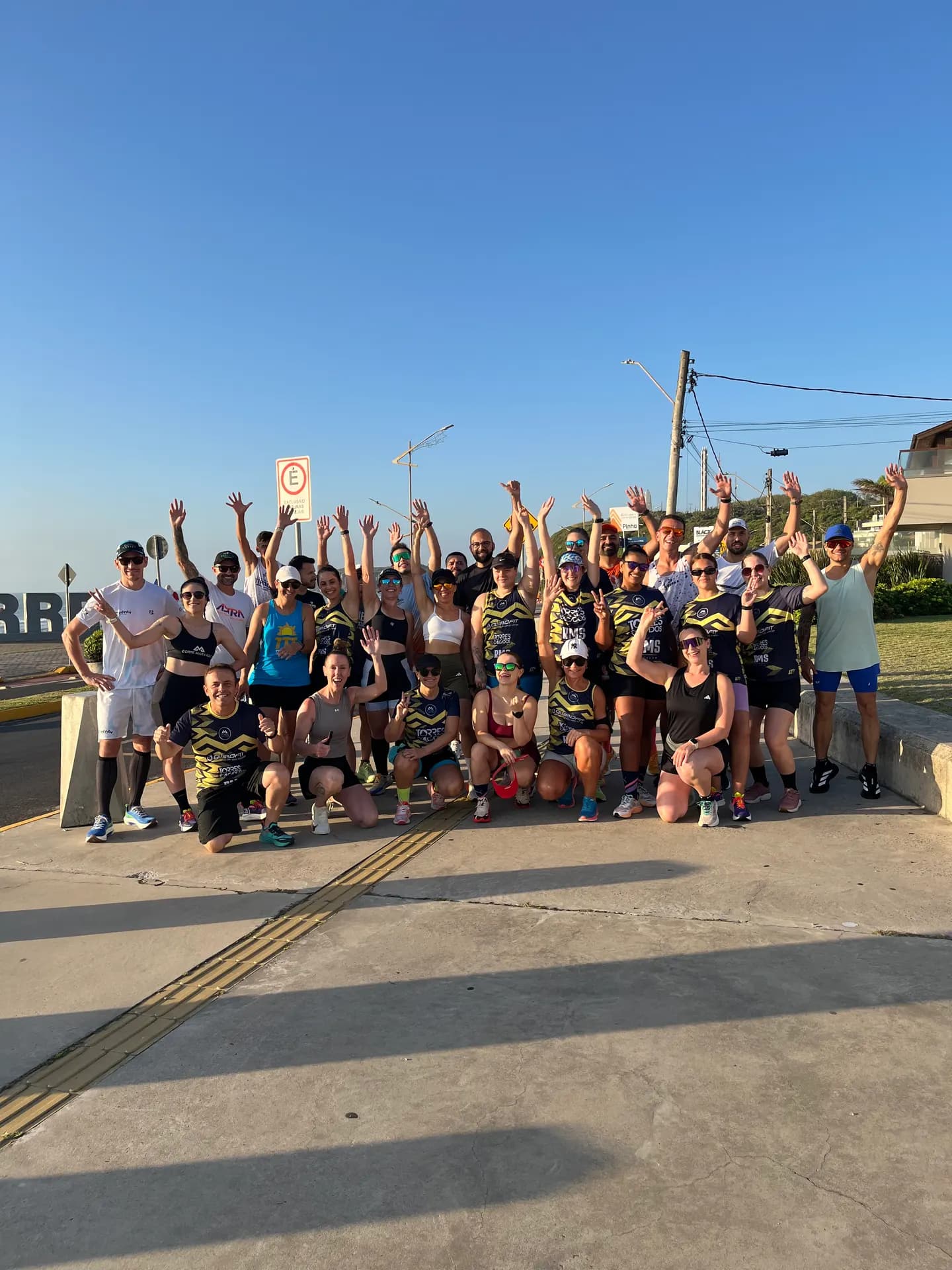 Dezenas de corredores da Corre Marvado reunidos em frente ao letreiro de Torres, braços erguidos depois do treino